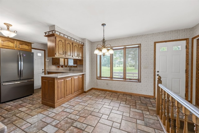 4519 Indian Creek Rd, Marion, IA 52302 - kitchen featuring freestanding refrigerator, light countertops, wallpapered walls, a chandelier, and a peninsula