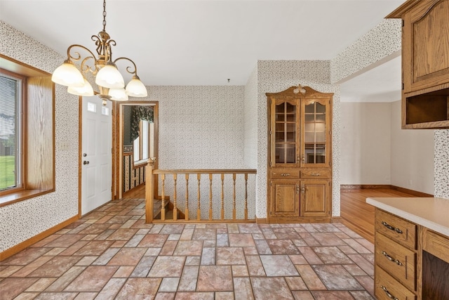 4519 Indian Creek Rd, Marion, IA 52302 - kitchen with wallpapered walls, a chandelier, baseboards, light countertops, and hanging light fixtures