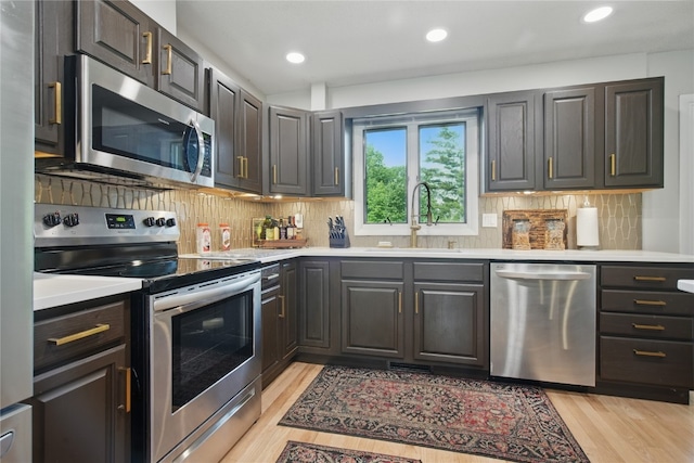 1649 Memorial Dr SE, Cedar Rapids, IA 52403 - kitchen with stainless steel appliances, a sink, light countertops, light wood-style floors, and decorative backsplash