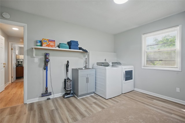 1649 Memorial Dr SE, Cedar Rapids, IA 52403 - washroom featuring washing machine and dryer, cabinet space, light wood-style floors, and baseboards