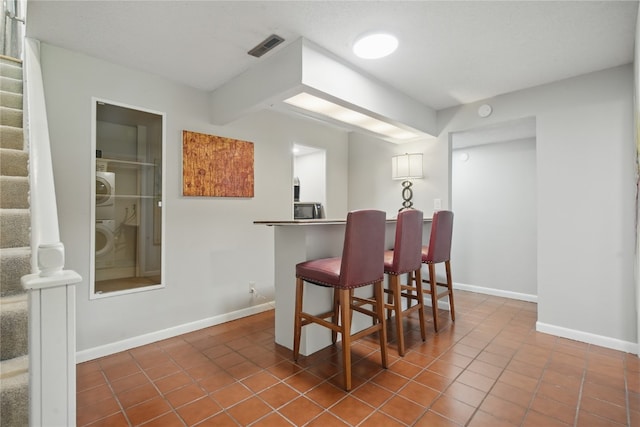 1649 Memorial Dr SE, Cedar Rapids, IA 52403 - indoor dry bar featuring stacked washing machine and dryer, stairway, baseboards, and tile patterned flooring