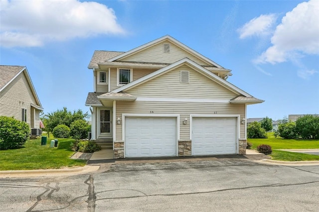 1450 Tower Ln NE, Cedar Rapids, IA 52402 - traditional home with stone siding, asphalt driveway, central air condition unit, and a front lawn