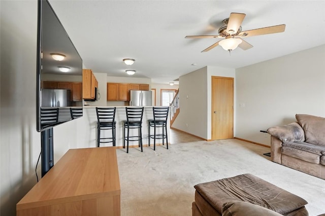 1450 Tower Ln NE, Cedar Rapids, IA 52402 - living room featuring light colored carpet, a ceiling fan, baseboards, and stairs