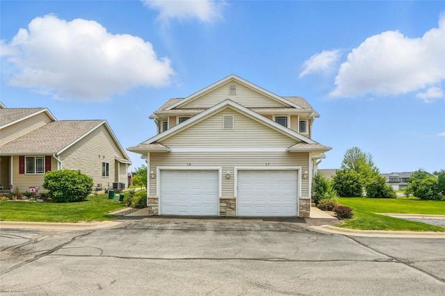 1450 Tower Ln NE, Cedar Rapids, IA 52402 - view of front of house featuring stone siding, a garage, driveway, and a front yard