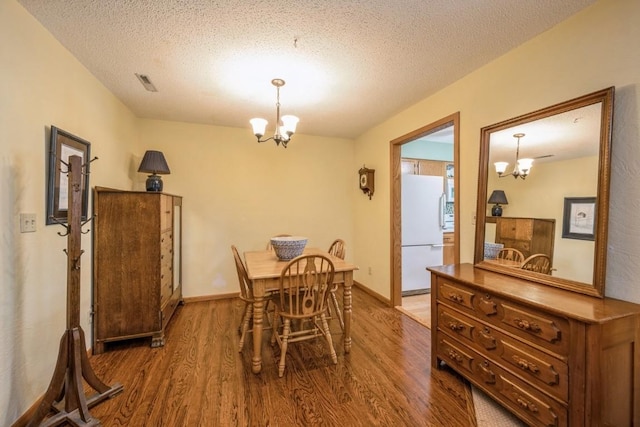 4320 Maureen Ct SE Unit 176, Cedar Rapids, IA 52403 - dining room with a chandelier, wood finished floors, a textured ceiling, and baseboards