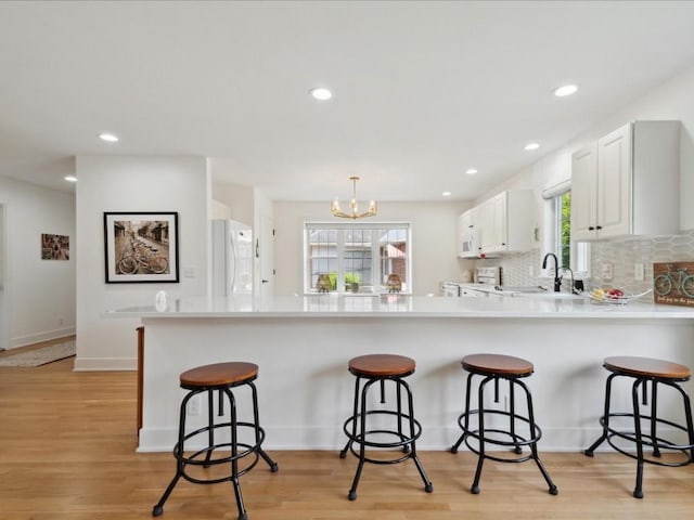 501 Washington Ct SW Unit B, Mount Vernon, IA 52314 - kitchen with white appliances, a breakfast bar, a chandelier, a peninsula, and recessed lighting