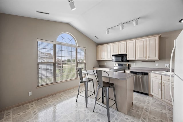 4960 Lucore Rd, Marion, IA 52302 - kitchen featuring appliances with stainless steel finishes, rail lighting, lofted ceiling, a kitchen island, and a breakfast bar