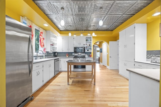 508 W 5th St, Vinton, IA 52349 - kitchen with appliances with stainless steel finishes, open shelves, an ornate ceiling, arched walkways, and decorative backsplash