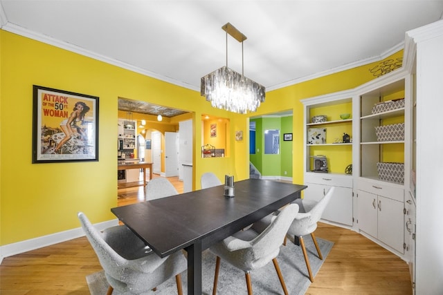 508 W 5th St, Vinton, IA 52349 - dining area with ornamental molding, a chandelier, light wood-style flooring, arched walkways, and baseboards