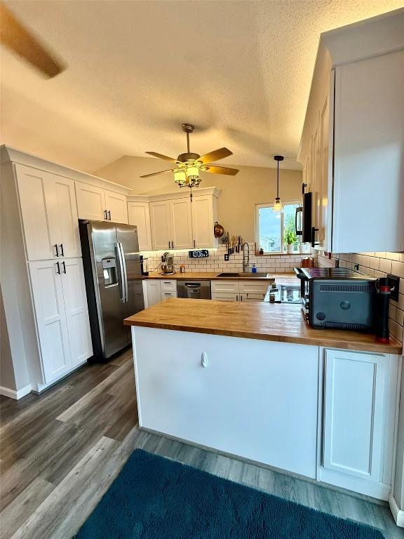 828 73rd NE, Cedar Rapids, IA 52402 - kitchen with appliances with stainless steel finishes, wooden counters, a peninsula, decorative backsplash, and vaulted ceiling