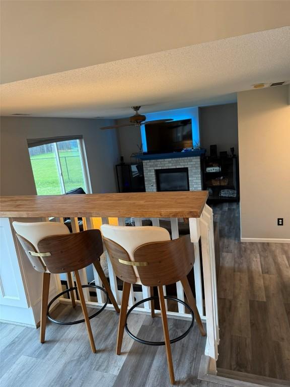 828 73rd NE, Cedar Rapids, IA 52402 - dining space with a brick fireplace, ceiling fan, wood finished floors, and a textured ceiling