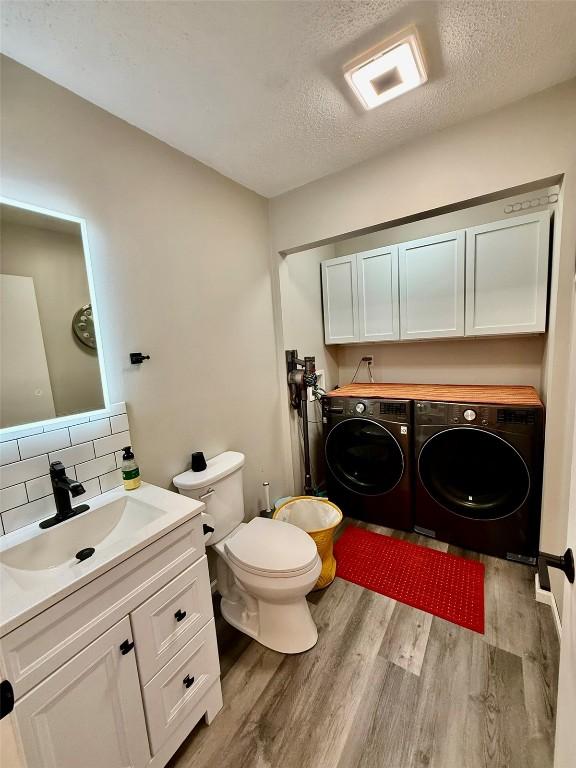 828 73rd NE, Cedar Rapids, IA 52402 - bathroom featuring washing machine and clothes dryer, wood finished floors, tasteful backsplash, vanity, and a textured ceiling