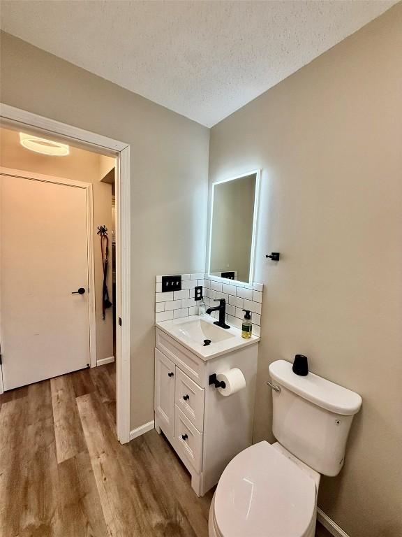 828 73rd NE, Cedar Rapids, IA 52402 - bathroom with vanity, wood finished floors, a textured ceiling, and tasteful backsplash