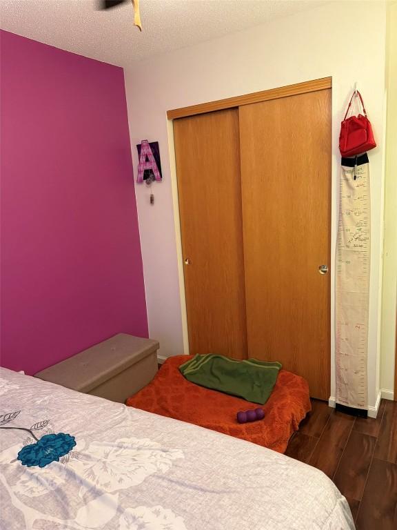 828 73rd NE, Cedar Rapids, IA 52402 - bedroom featuring wood finished floors, a closet, a textured ceiling, and ceiling fan