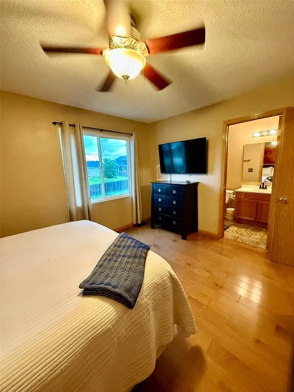828 73rd NE, Cedar Rapids, IA 52402 - bedroom with light wood-style floors, a textured ceiling, ceiling fan, and ensuite bath