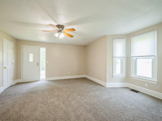 207 Prospect St NW, Blairstown, IA 52209 - unfurnished living room featuring ceiling fan, a textured ceiling, and carpet