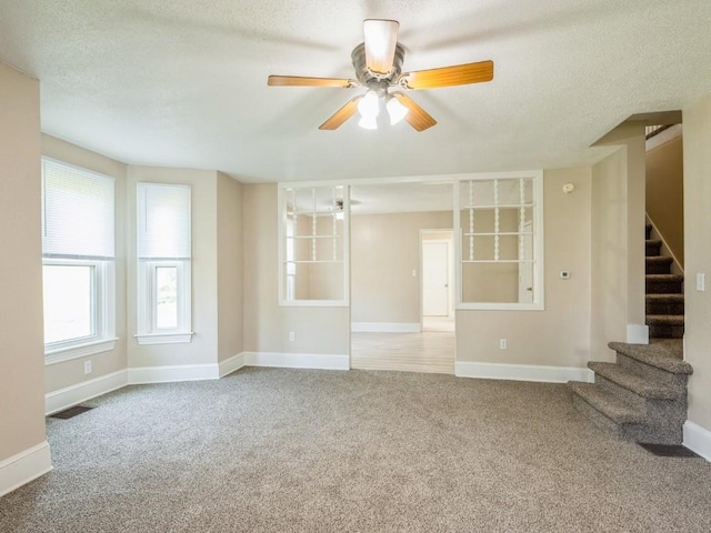 207 Prospect St NW, Blairstown, IA 52209 - unfurnished living room with carpet floors, stairs, a ceiling fan, and a textured ceiling