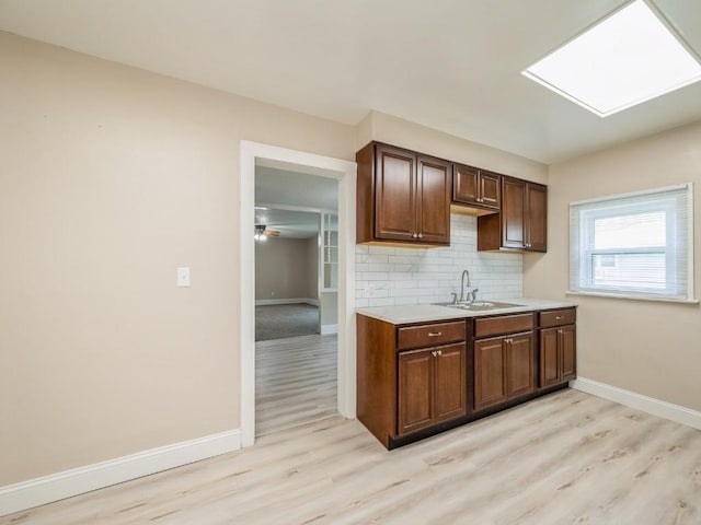 207 Prospect St NW, Blairstown, IA 52209 - kitchen featuring light wood-style floors, light countertops, tasteful backsplash, and a skylight