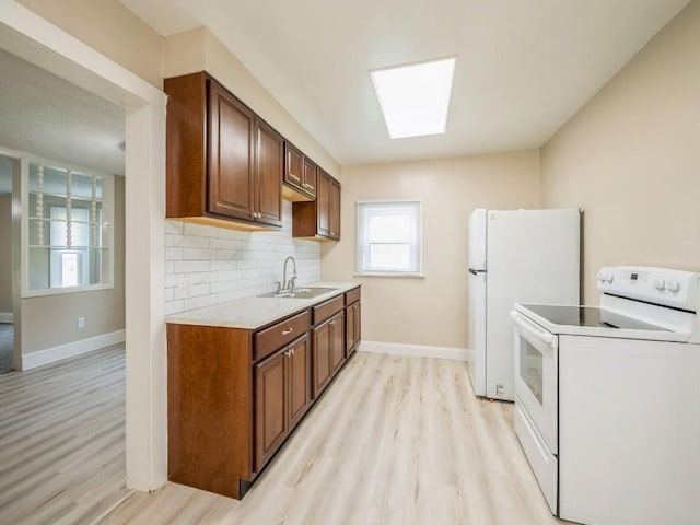 207 Prospect St NW, Blairstown, IA 52209 - kitchen with white appliances, light wood-style floors, light countertops, decorative backsplash, and a skylight