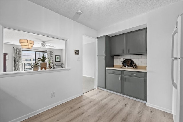 130 Thompson Dr SE Unit 320, Cedar Rapids, IA 52403 - kitchen with gray cabinetry, light wood-style floors, tasteful backsplash, freestanding refrigerator, and a textured ceiling