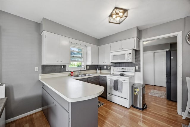3622 14th Ave SE, Cedar Rapids, IA 52403 - kitchen featuring white appliances, a peninsula, tasteful backsplash, light countertops, and white cabinets