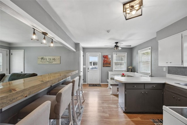 3622 14th Ave SE, Cedar Rapids, IA 52403 - kitchen featuring a peninsula, light wood-style flooring, light countertops, a ceiling fan, and a kitchen breakfast bar