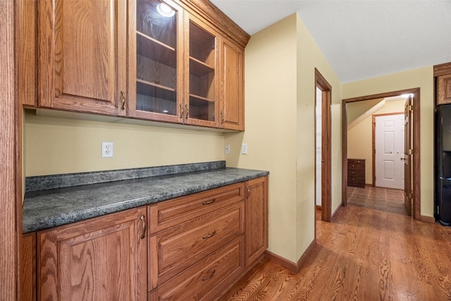 660 Garfield Rd, West Branch, IA 52358 - kitchen featuring dark countertops, wood finished floors, brown cabinets, and glass insert cabinets