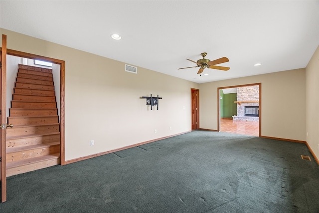 660 Garfield Rd, West Branch, IA 52358 - carpeted spare room featuring ceiling fan, stairs, a stone fireplace, and recessed lighting