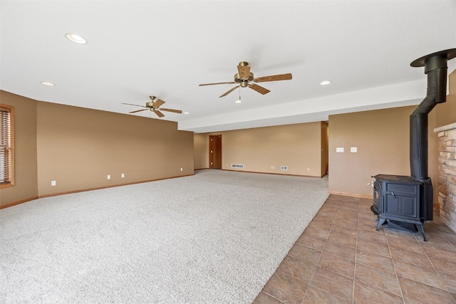 660 Garfield Rd, West Branch, IA 52358 - unfurnished living room featuring a wood stove, a ceiling fan, recessed lighting, light colored carpet, and light tile patterned flooring