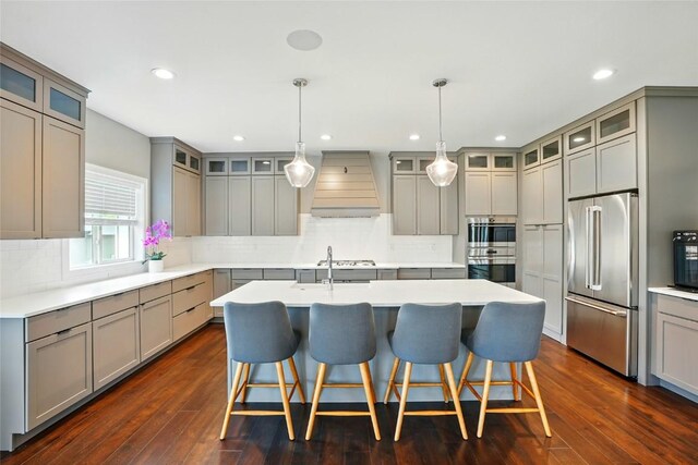 1643 Avalon Pl, Iowa City, IA 52245 - kitchen with appliances with stainless steel finishes, custom exhaust hood, gray cabinets, a center island with sink, and tasteful backsplash
