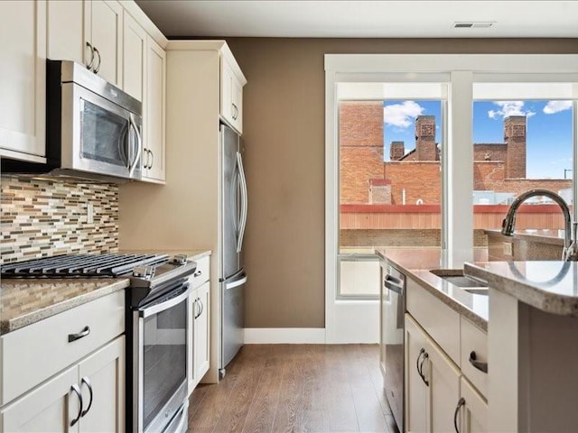 100 4th Ave SW Unit 204, Cedar Rapids, IA 52404 - kitchen featuring appliances with stainless steel finishes, wood finished floors, decorative backsplash, light stone countertops, and white cabinets