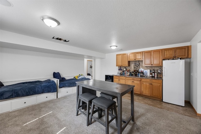 429 W Prairie Dr, Fairfax, IA 52228 - kitchen featuring freestanding refrigerator, open floor plan, a textured ceiling, tasteful backsplash, and brown cabinetry