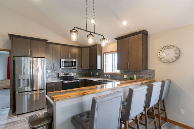310 34th Ave, Marion, IA 52302 - kitchen featuring appliances with stainless steel finishes, decorative backsplash, dark brown cabinets, a peninsula, and a breakfast bar