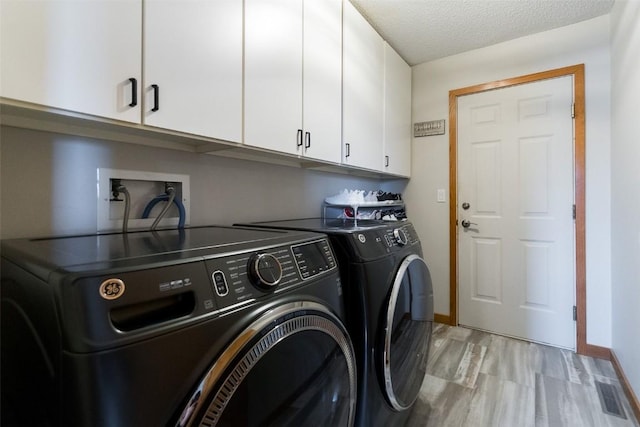 310 34th Ave, Marion, IA 52302 - laundry room with cabinet space, washer and clothes dryer, light wood-type flooring, and a textured ceiling