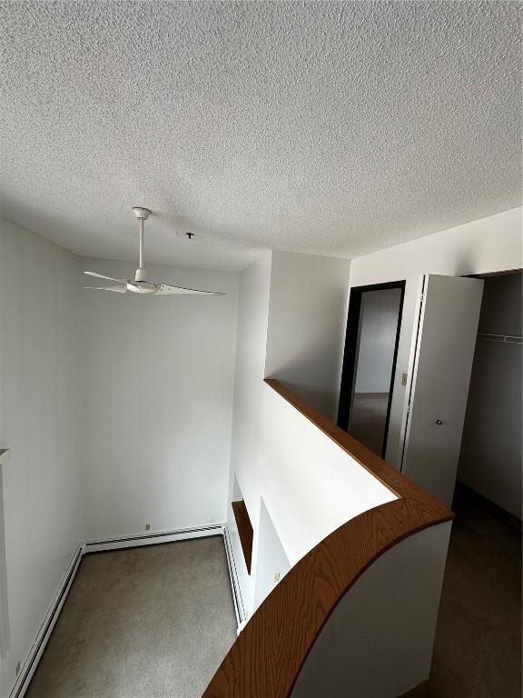400 1st St SE Unit 410, Cedar Rapids, IA 52401 - hallway featuring baseboard heating, carpet flooring, and a textured ceiling