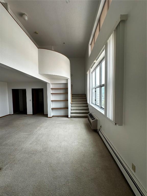 400 1st St SE Unit 410, Cedar Rapids, IA 52401 - unfurnished living room with a baseboard radiator, carpet floors, and stairway