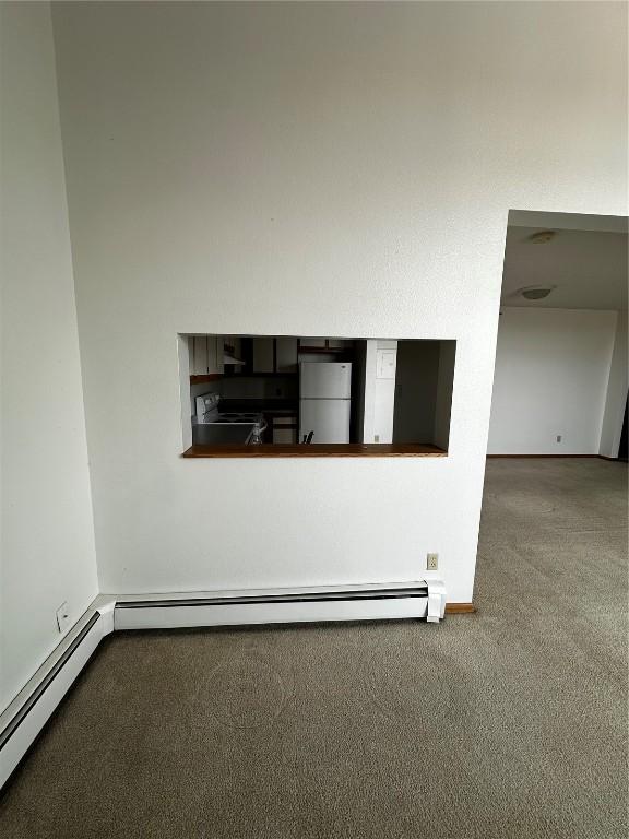 400 1st St SE Unit 410, Cedar Rapids, IA 52401 - detailed view of freestanding refrigerator, carpet floors, and a baseboard radiator