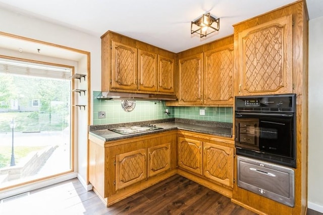 2175 Chandler St SW, Cedar Rapids, IA 52404 - kitchen with black oven, dark countertops, brown cabinets, tasteful backsplash, and stovetop
