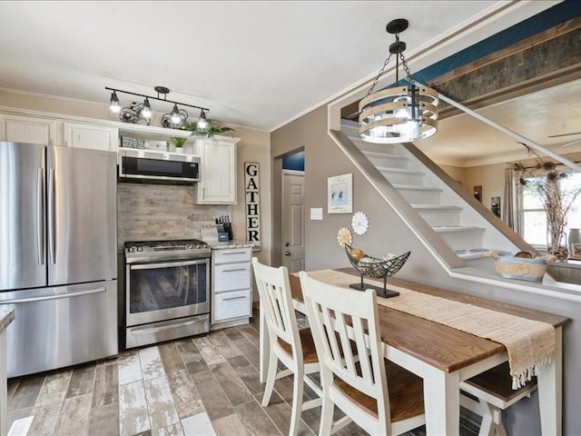 1418 8th St NW, Cedar Rapids, IA 52405 - kitchen with appliances with stainless steel finishes, crown molding, backsplash, light wood-style floors, and hanging light fixtures