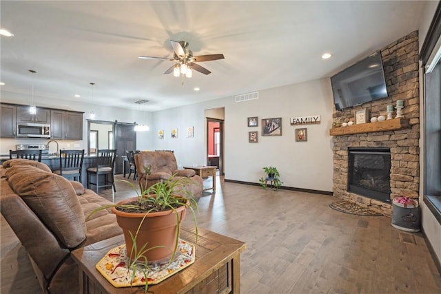 1602 Bridge Creek Ct, Marion, IA 52302 - living area featuring a barn door, a ceiling fan, recessed lighting, light wood-type flooring, and a fireplace