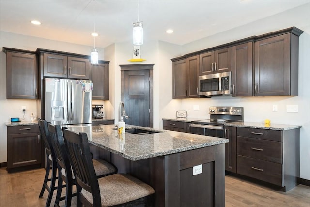 1602 Bridge Creek Ct, Marion, IA 52302 - kitchen featuring appliances with stainless steel finishes, light wood-style floors, dark brown cabinetry, stone countertops, and recessed lighting