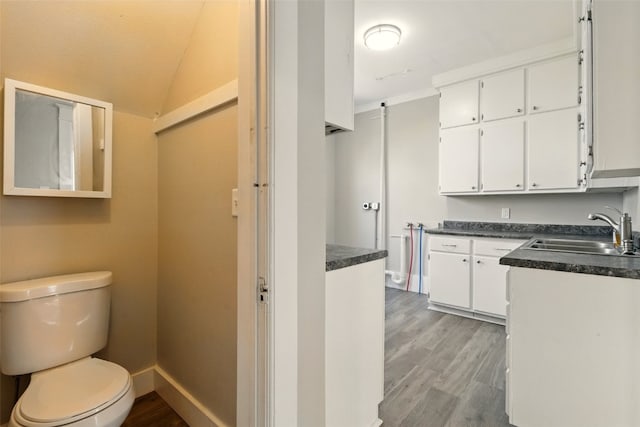 216 15th St NE, Cedar Rapids, IA 52402 - kitchen with white cabinets, dark countertops, light wood-style floors, and vaulted ceiling