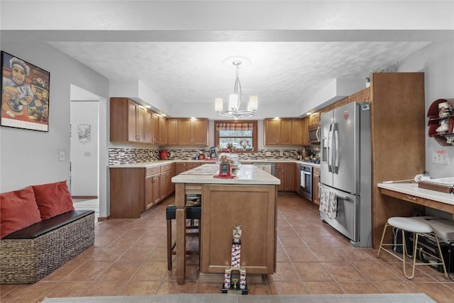 2145 Coldstream Ave NE, Cedar Rapids, IA 52402 - kitchen with appliances with stainless steel finishes, a chandelier, light countertops, decorative backsplash, and a kitchen bar