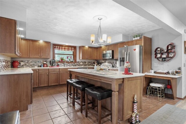 2145 Coldstream Ave NE, Cedar Rapids, IA 52402 - kitchen with appliances with stainless steel finishes, light countertops, a kitchen island, a kitchen breakfast bar, and backsplash