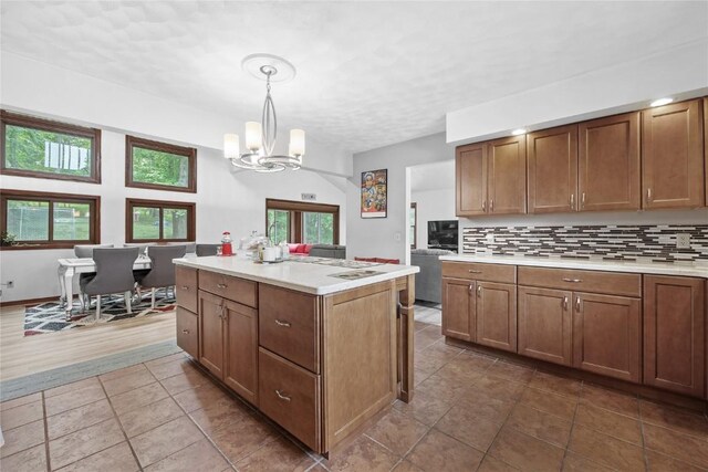 2145 Coldstream Ave NE, Cedar Rapids, IA 52402 - kitchen featuring a chandelier, light countertops, a center island, backsplash, and brown cabinets