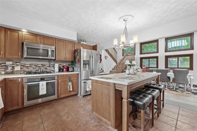 2145 Coldstream Ave NE, Cedar Rapids, IA 52402 - kitchen featuring stainless steel appliances, a chandelier, brown cabinets, and light countertops
