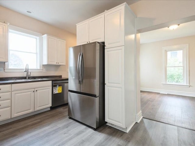 1308 A Ave NW, Cedar Rapids, IA 52405 - kitchen with appliances with stainless steel finishes, dark countertops, light wood-style floors, and white cabinets
