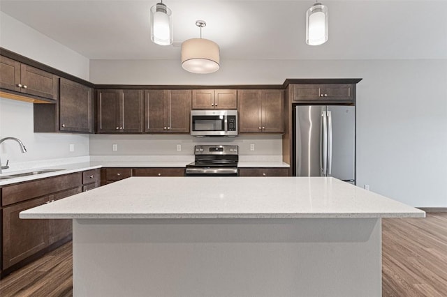 2871 Spring Rose Cir Unit 207, Coralville, IA 52241 - kitchen featuring appliances with stainless steel finishes, dark brown cabinets, wood finished floors, a kitchen island, and hanging light fixtures
