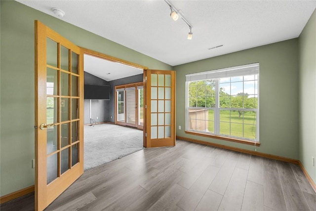 3110 Towne House Dr NE Unit C, Cedar Rapids, IA 52402 - unfurnished room featuring french doors, wood finished floors, rail lighting, vaulted ceiling, and a smoke detector