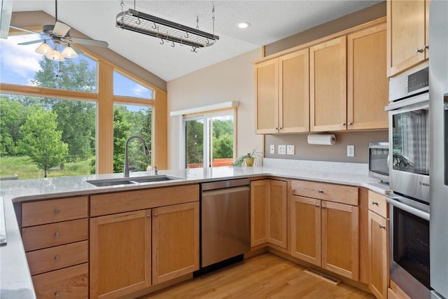 218 Teakwood Ln NE, Cedar Rapids, IA 52402 - kitchen with stainless steel appliances, light brown cabinetry, vaulted ceiling, light wood-style floors, and light countertops